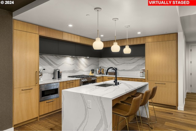 kitchen featuring a kitchen island with sink, pendant lighting, sink, dark hardwood / wood-style flooring, and tasteful backsplash