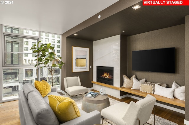 living room with floor to ceiling windows, a large fireplace, hardwood / wood-style flooring, and a healthy amount of sunlight