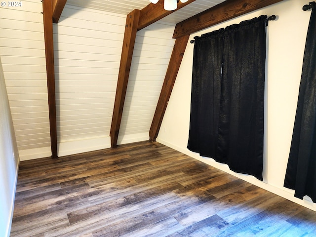 unfurnished bedroom featuring dark hardwood / wood-style floors, beam ceiling, and wooden walls