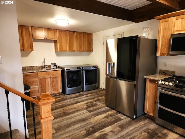 kitchen with sink, washing machine and clothes dryer, stainless steel appliances, beamed ceiling, and dark wood-type flooring