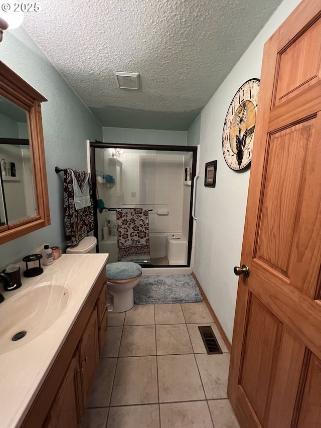 bathroom with tile patterned floors, toilet, an enclosed shower, a textured ceiling, and vanity