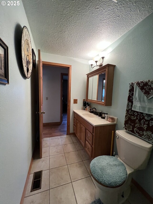 bathroom featuring tile patterned flooring, vanity, a textured ceiling, and toilet