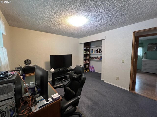 office space featuring built in shelves, dark carpet, and a textured ceiling