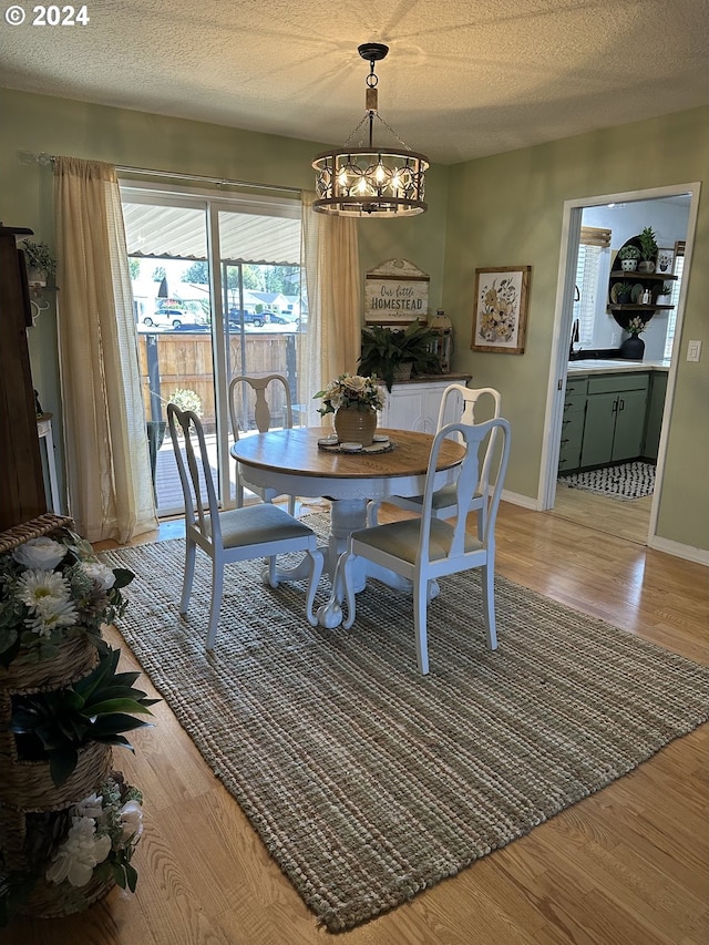 dining room with a textured ceiling, light wood-type flooring, and a chandelier