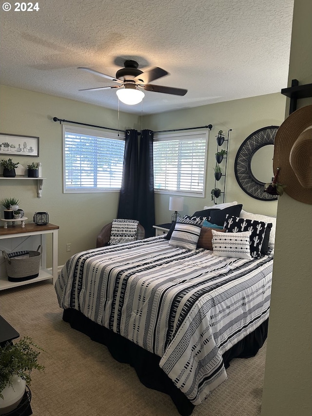 carpeted bedroom featuring ceiling fan and a textured ceiling