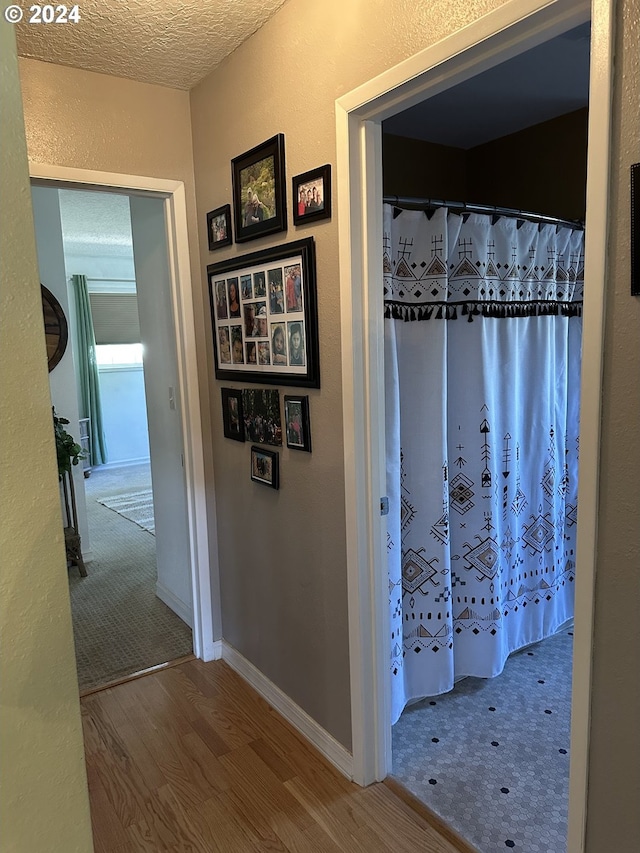 corridor with a textured ceiling and hardwood / wood-style floors