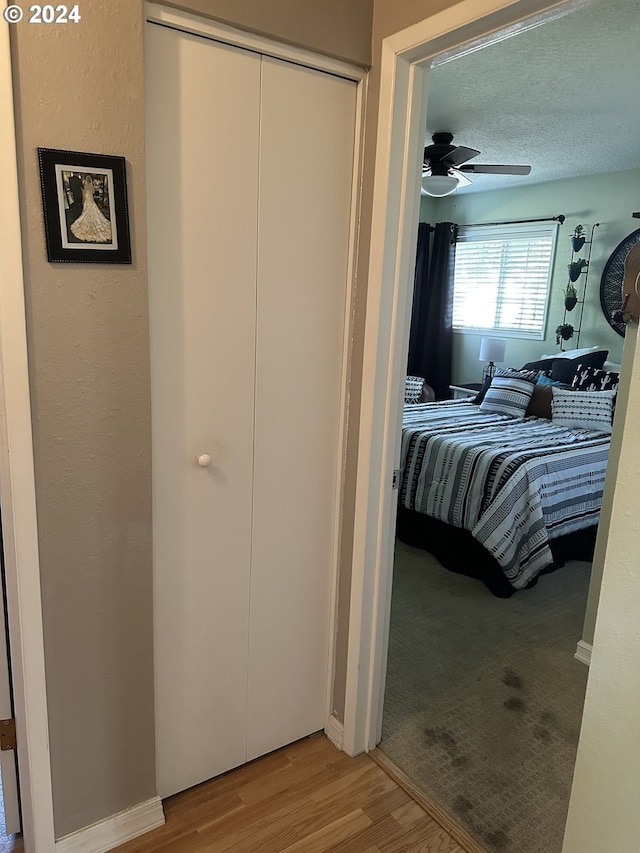 bedroom featuring ceiling fan, hardwood / wood-style flooring, a closet, and a textured ceiling