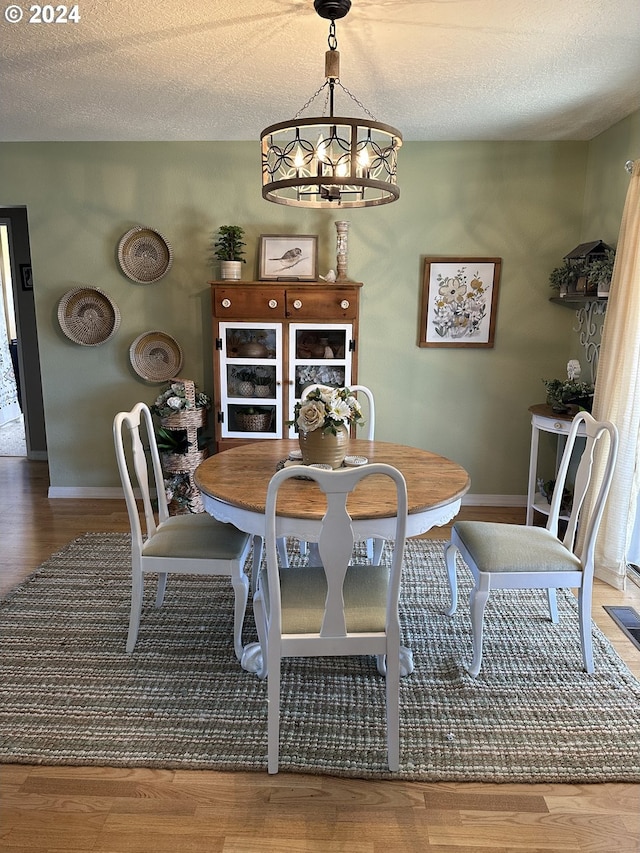 dining space featuring a textured ceiling, wood-type flooring, and a chandelier