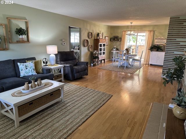 living room with a notable chandelier, wood-type flooring, and a textured ceiling