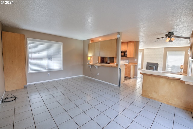 kitchen with kitchen peninsula, light brown cabinets, a textured ceiling, and a breakfast bar area