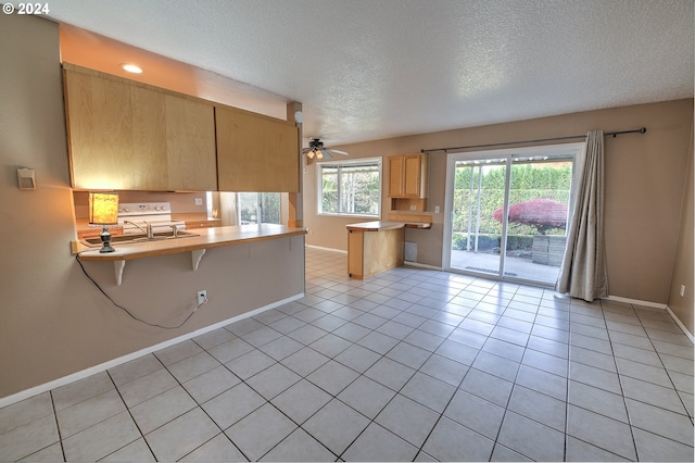 kitchen featuring kitchen peninsula, a breakfast bar, light tile patterned floors, and a textured ceiling