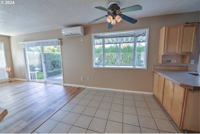 kitchen with ceiling fan, plenty of natural light, a wall mounted air conditioner, and light hardwood / wood-style flooring