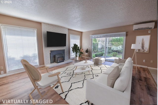 living room featuring a wood stove, a textured ceiling, hardwood / wood-style flooring, and a wall unit AC