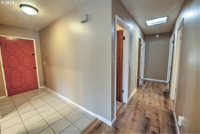 corridor with a textured ceiling and light wood-type flooring