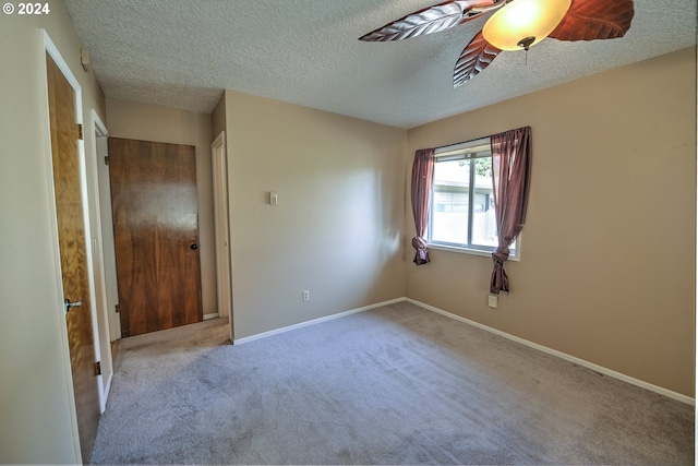 carpeted empty room with ceiling fan and a textured ceiling