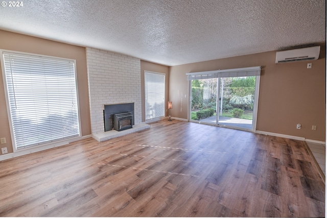 unfurnished living room with a textured ceiling, hardwood / wood-style floors, and a wall mounted air conditioner