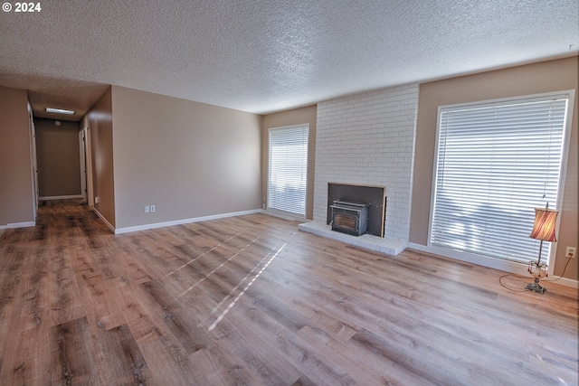 unfurnished living room with a textured ceiling, a wealth of natural light, and light hardwood / wood-style flooring