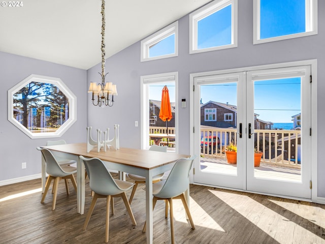 dining area with hardwood / wood-style floors, high vaulted ceiling, french doors, and a notable chandelier