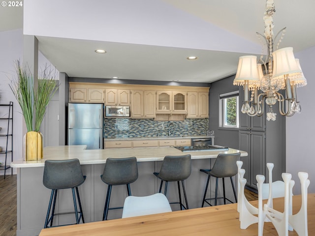 kitchen with a breakfast bar, dark hardwood / wood-style floors, lofted ceiling, backsplash, and appliances with stainless steel finishes