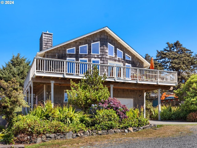 exterior space with an attached garage, a chimney, and a wooden deck
