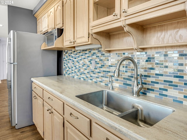 kitchen with light brown cabinets, sink, wood-type flooring, backsplash, and stainless steel appliances