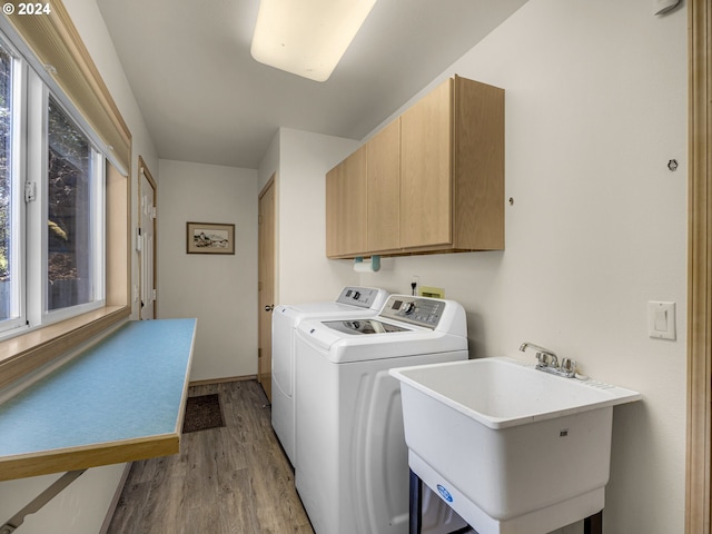 washroom with light wood-type flooring, a healthy amount of sunlight, sink, and cabinets