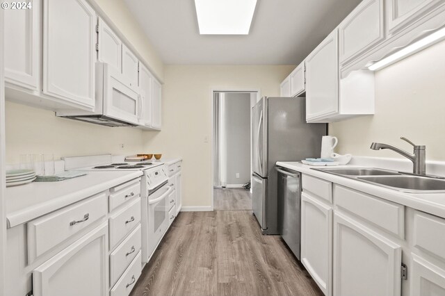 kitchen with sink, white appliances, light hardwood / wood-style floors, and white cabinetry