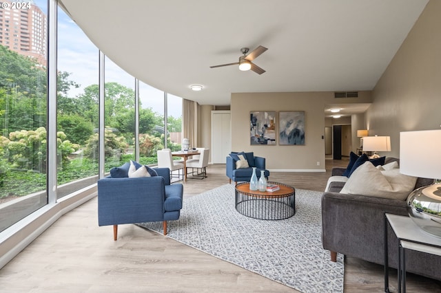 living room featuring expansive windows, ceiling fan, and light wood-type flooring