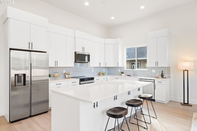 kitchen with a center island, sink, a breakfast bar, white cabinetry, and appliances with stainless steel finishes