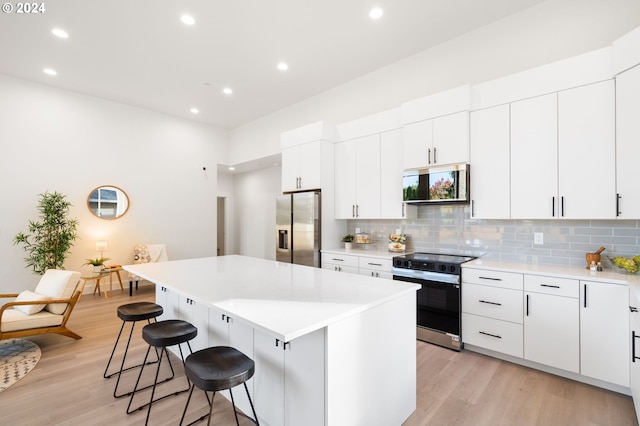 kitchen featuring white cabinetry, light wood-type flooring, appliances with stainless steel finishes, and a center island