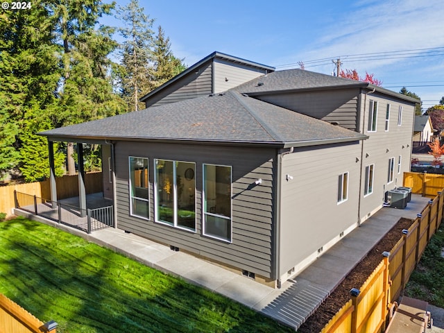 rear view of property featuring central AC unit, a patio area, and a yard