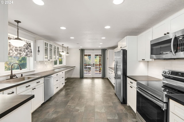 kitchen with appliances with stainless steel finishes, sink, a healthy amount of sunlight, and white cabinets