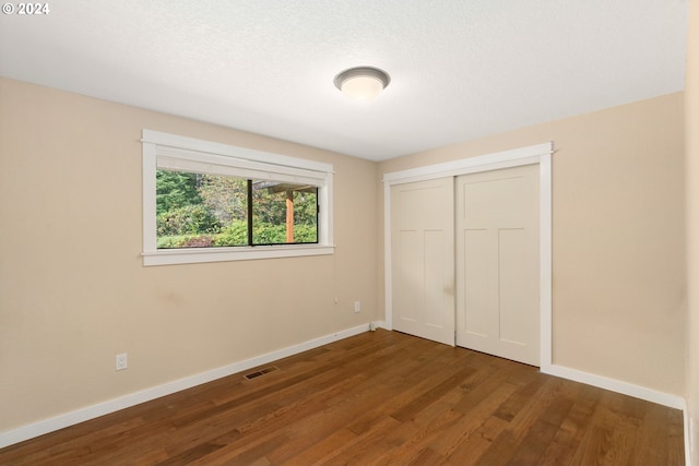 unfurnished bedroom with dark hardwood / wood-style floors, a textured ceiling, and a closet