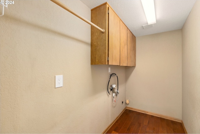 laundry area featuring cabinets, a textured ceiling, and dark hardwood / wood-style flooring