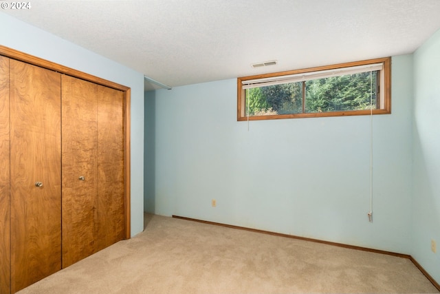 unfurnished bedroom with light carpet, a closet, and a textured ceiling