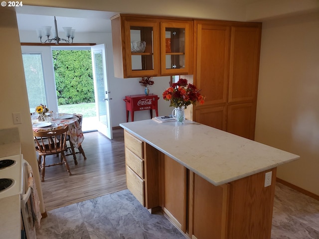 kitchen featuring an inviting chandelier, light hardwood / wood-style flooring, light stone countertops, and white stove