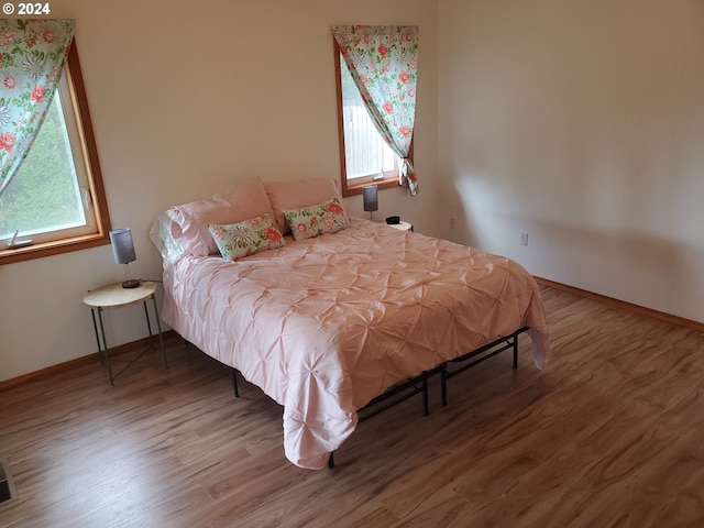 bedroom with multiple windows and hardwood / wood-style floors