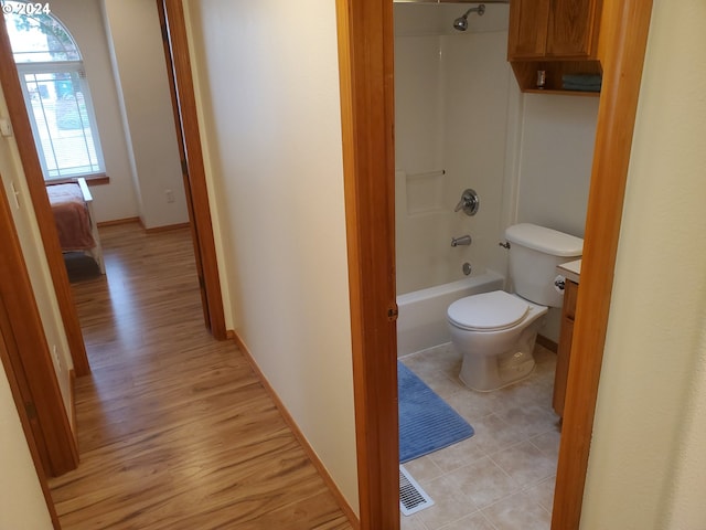 bathroom featuring hardwood / wood-style floors, shower / tub combination, and toilet