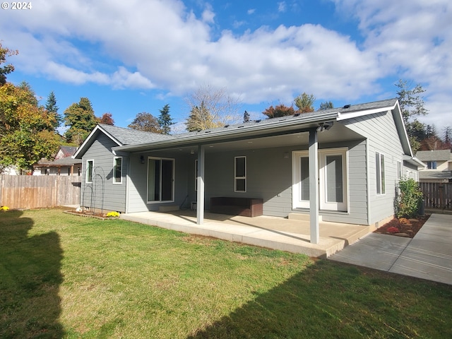 back of property featuring a patio area and a lawn