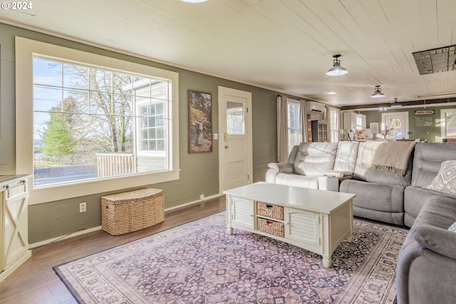 living room with a wall unit AC, a wealth of natural light, and light hardwood / wood-style floors