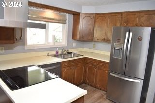 kitchen with hardwood / wood-style floors, sink, ventilation hood, stainless steel fridge with ice dispenser, and black electric cooktop