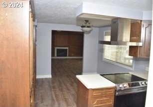 kitchen featuring stainless steel electric range oven, dark wood-type flooring, a textured ceiling, and wall chimney range hood