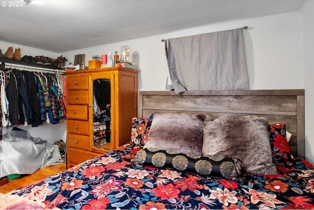 bedroom with ornamental molding, hardwood / wood-style floors, and a closet