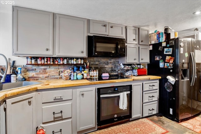 kitchen with sink, gray cabinetry, wooden counters, decorative backsplash, and black appliances