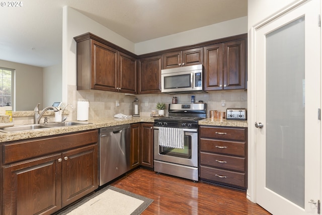 kitchen with backsplash, dark hardwood / wood-style flooring, stainless steel appliances, and sink