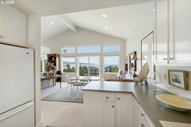 kitchen featuring beam ceiling, white refrigerator, kitchen peninsula, light colored carpet, and white cabinets