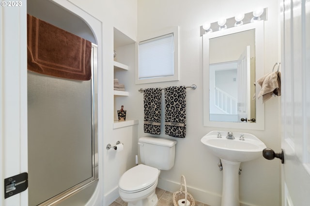 bathroom featuring tile patterned flooring, toilet, and shower / bath combination with glass door