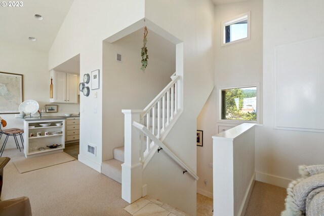 stairs featuring carpet and high vaulted ceiling