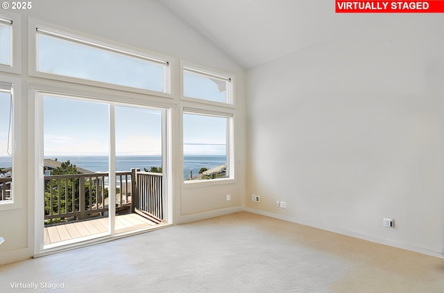 carpeted empty room featuring a water view and vaulted ceiling