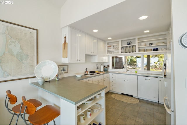 kitchen with kitchen peninsula, a breakfast bar, white appliances, sink, and white cabinets